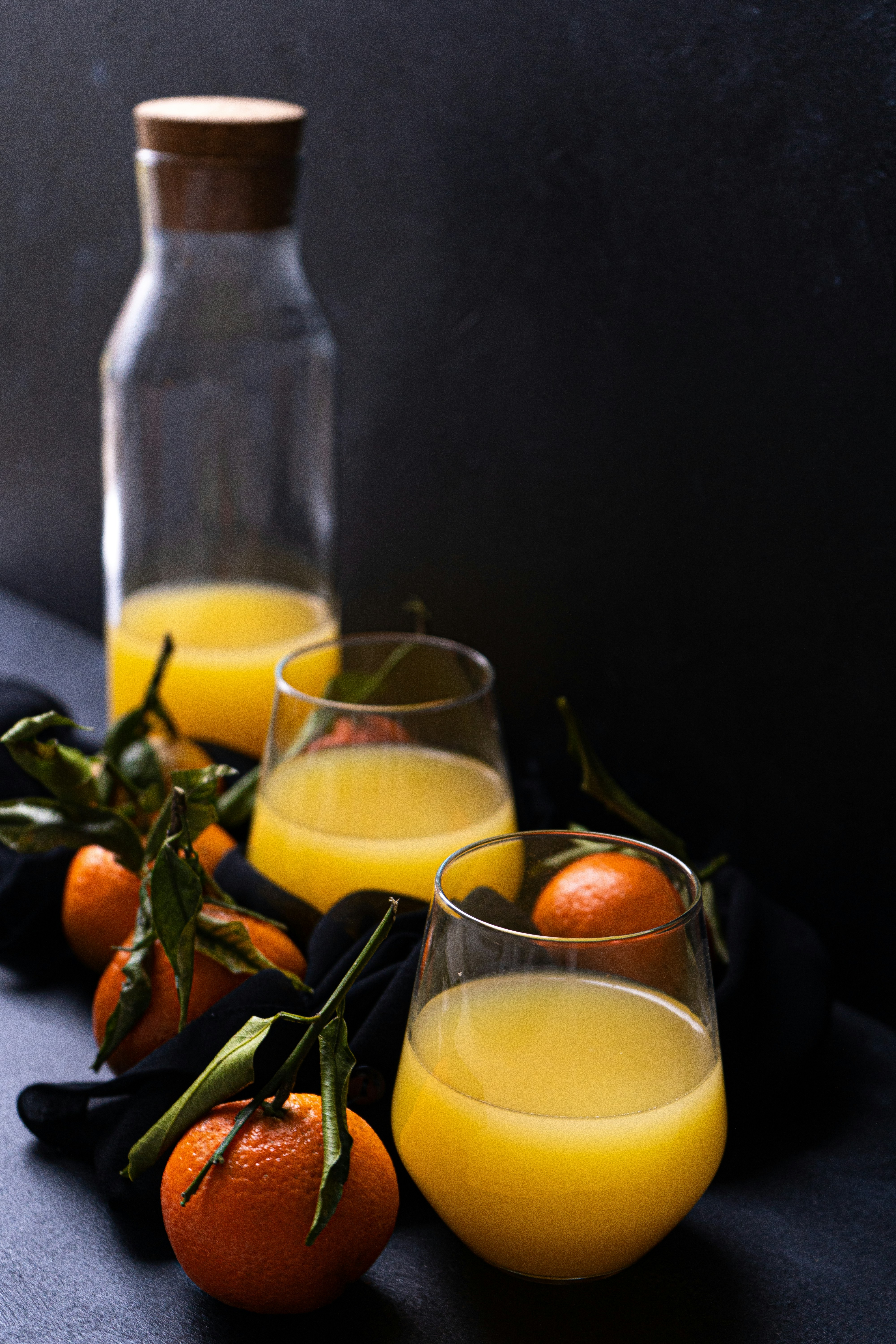 Fresh citrus juice in glass carafe and tumblers with whole tangerines