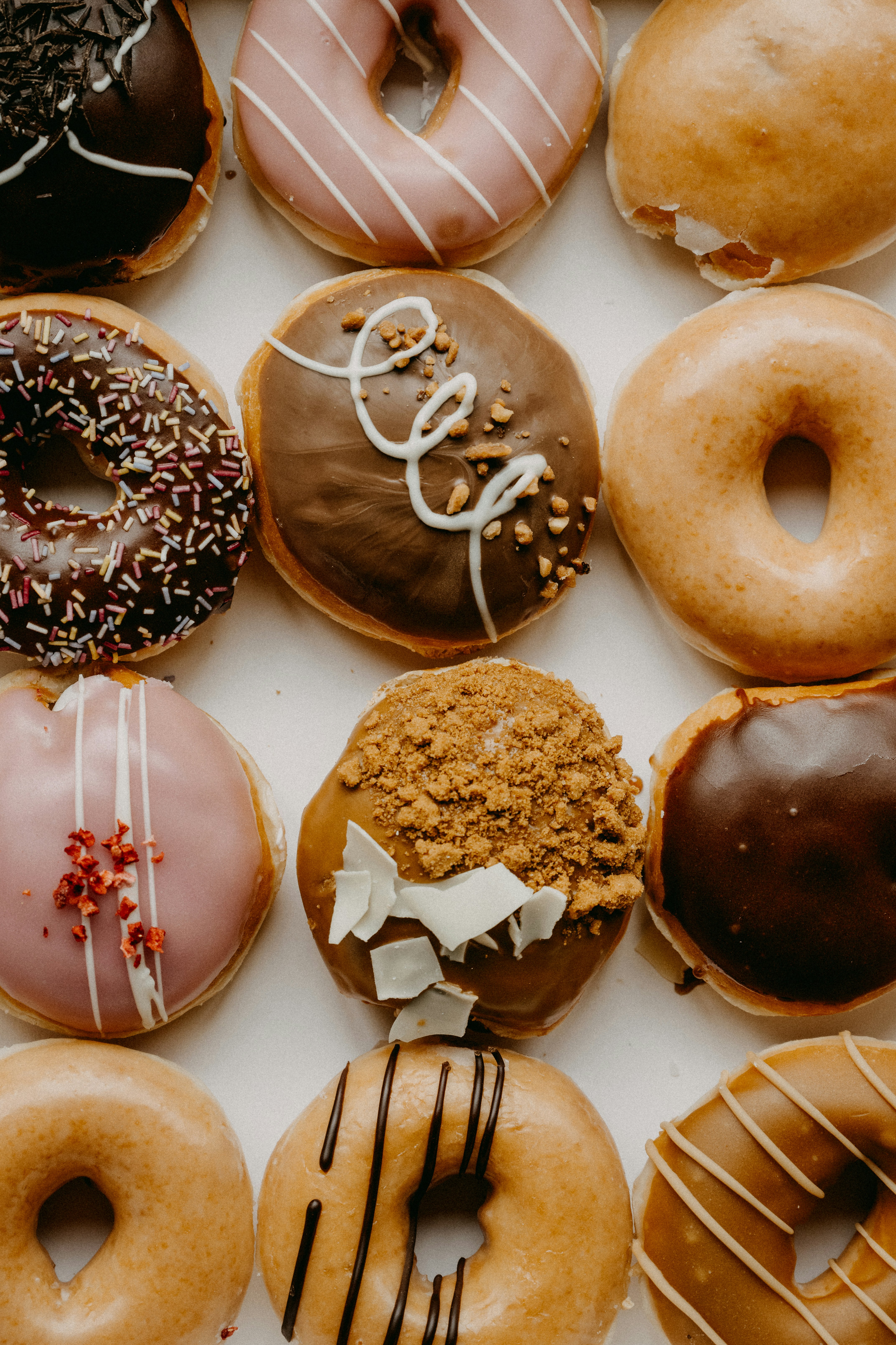 Assorted glazed and frosted donuts arranged in a white box