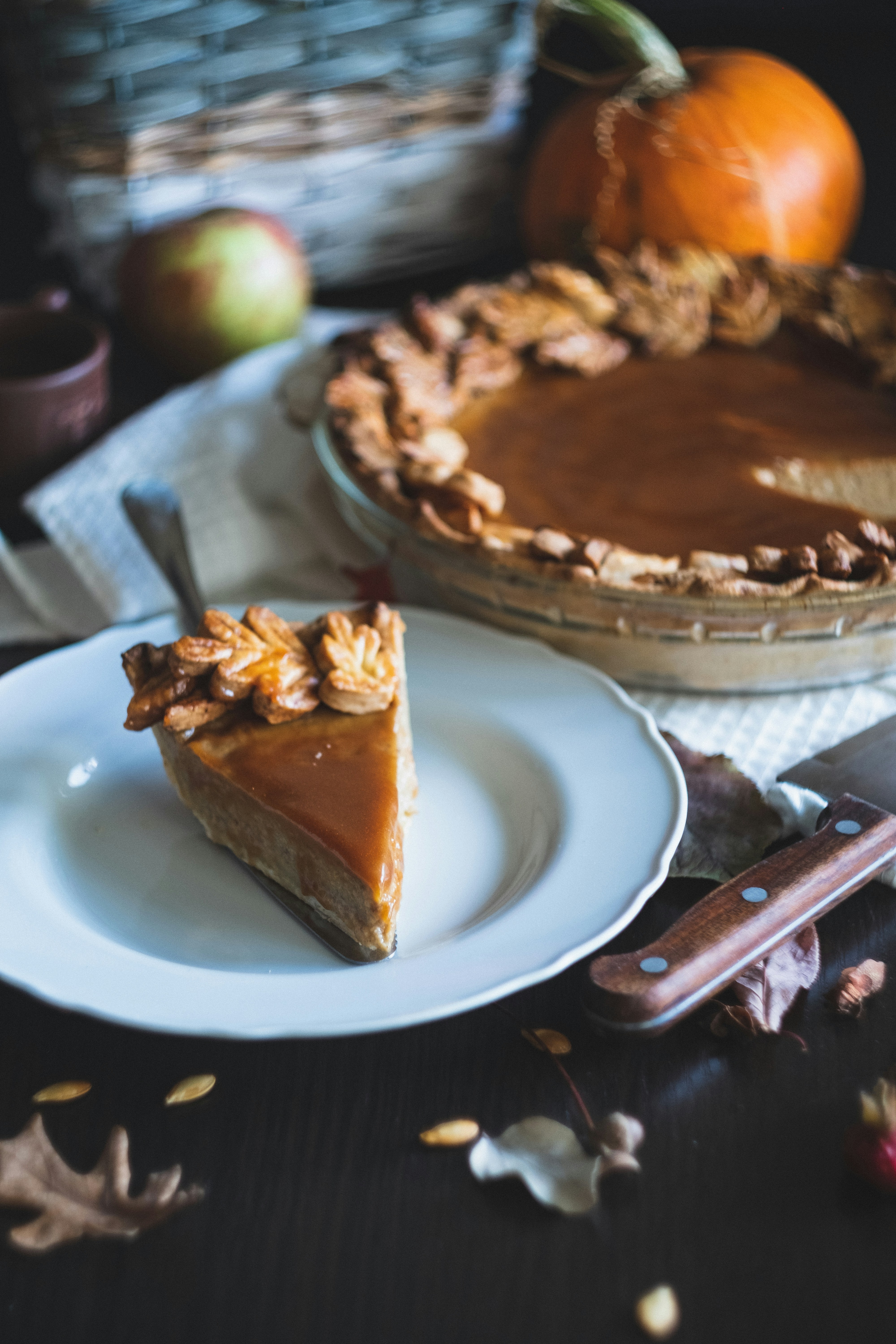 Slice of pumpkin pie with decorative leaf-shaped crust on a rustic table