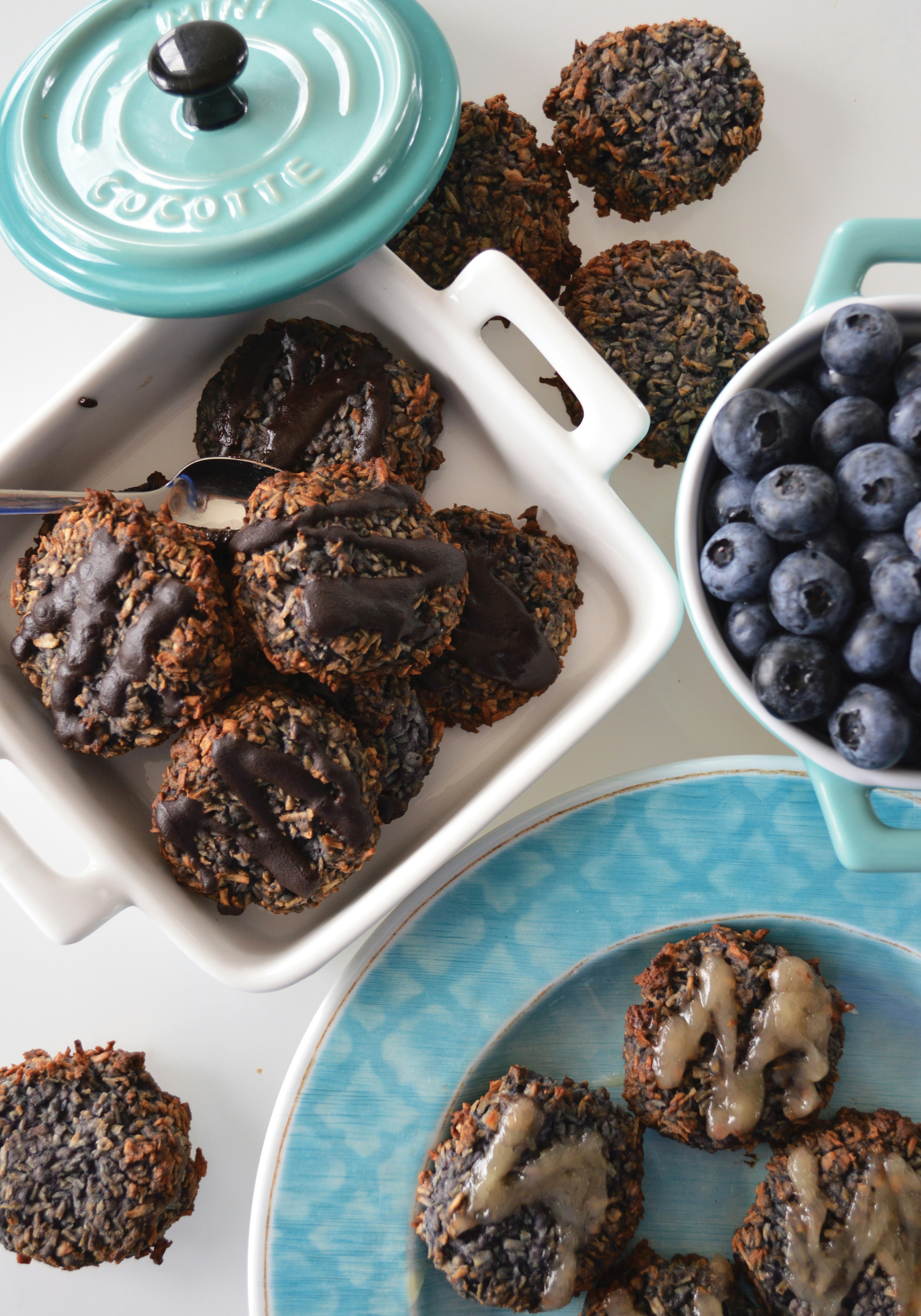 Chocolate-drizzled cookies with blueberries on a bright white surface