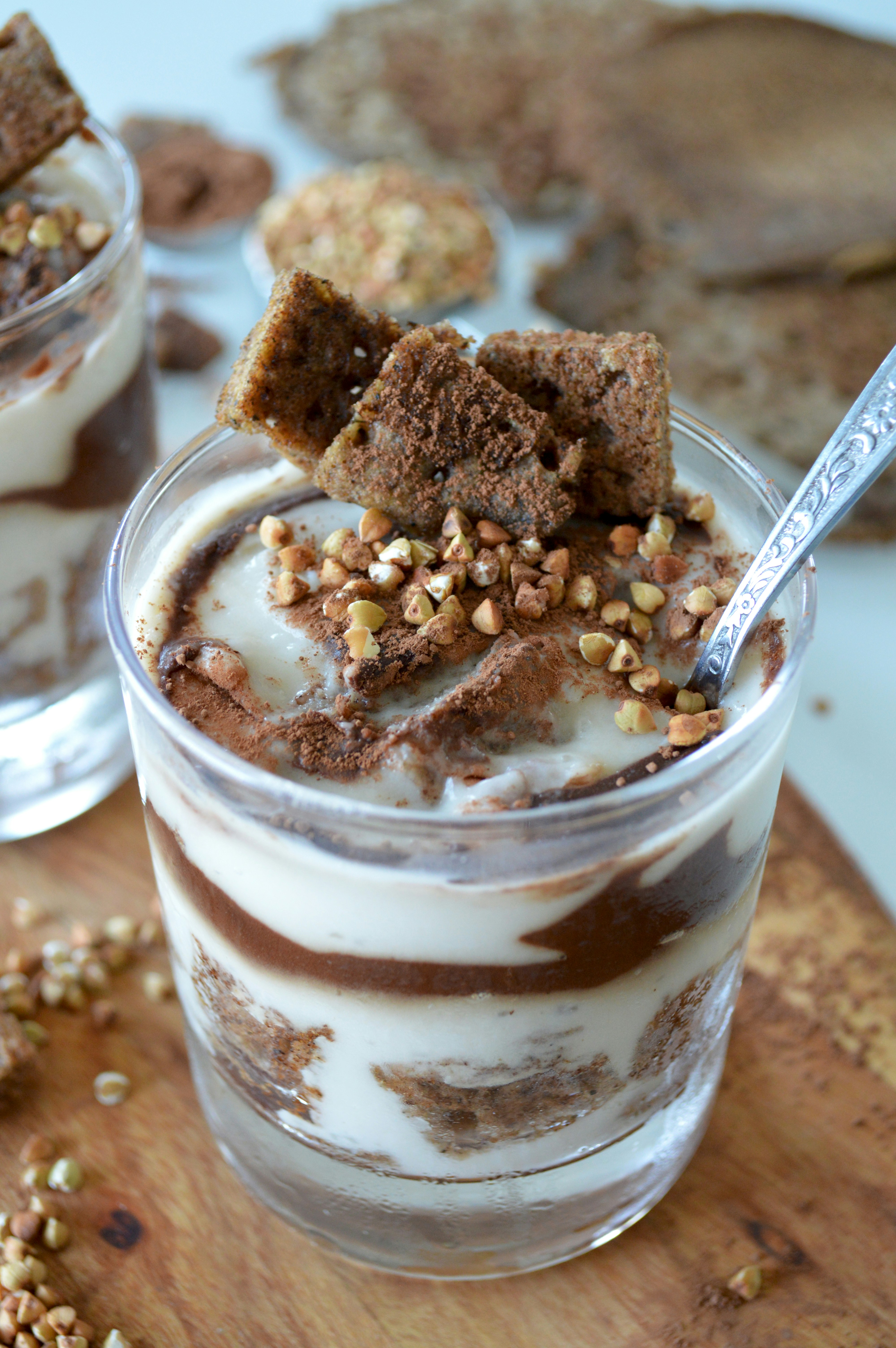 Layered chocolate and cream parfait in a glass with buckwheat topping